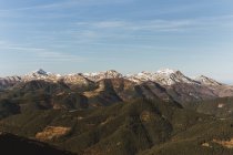 Panoramic view of green mountains with snowy peak on background of blue sky. — Stock Photo