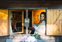 Side view of blonde girl with coffee in window of chalet — Stock Photo