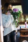Side view of romantic woman smelling flowers on porch — Stock Photo