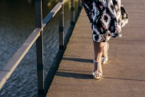 Жінка з низьким розділом в красивій сукні, що йде на мосту — стокове фото