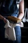 Mittelteil der Frau hält selbstgebackenen Kuchen auf Handtuch in Händen — Stockfoto