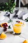 Bodegón de vidrio con zumo de naranja con bayas sobre mesa blanca - foto de stock