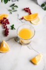 Low angle view of glass with orange juice with berries on table with white tablecloth — Stock Photo