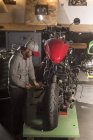 Professional mechanic fixing custom motorbike at workshop — Stock Photo