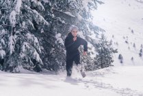Frontansicht einer sportlichen Frau, die schnell durch verschneite Landschaft läuft — Stockfoto