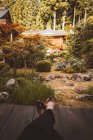 Crop legs of person sitting and resting in traditional Asian garden. — Stock Photo