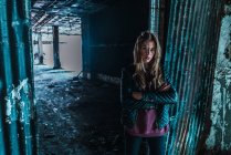Young woman standing at doorway and posing in grungy old building. — Stock Photo