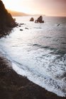 Спокійні хвилі на узбережжі з камінням під час заходу сонця . — стокове фото