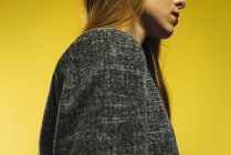 Crop woman in gray jacket on yellow background. — Stock Photo