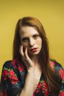 Portrait of redhead woman touching face and looking at camera — Stock Photo