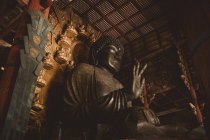 From below view to huge Buddha statue in Asian temple. — Stock Photo