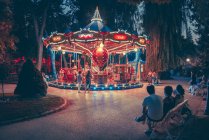 Merry-go-round illuminated carousel in green park at night. — Stock Photo