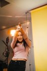 Joyeux jeune femme pistolet gesticulant et posant à la caméra en studio . — Photo de stock