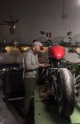 Seitenansicht des Mechanikers Befestigung benutzerdefinierte Motorrad in der Werkstatt — Stockfoto