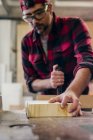 Tischler sägt in Werkstatt mit Motorsäge ein Stück Holz — Stockfoto