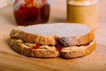 Закрыть вид на вкусный сэндвич с арахисовым маслом и желе на деревянном столе — стоковое фото