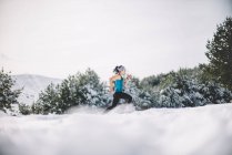 Вид сбоку на спортивную женщину, бегающую по снежному полю
. — стоковое фото