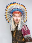 Retrato de homem com linha no rosto posando em traje nativo americano com olhos fechados no fundo branco — Fotografia de Stock
