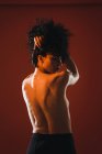 Visão traseira da mulher morena topless posando no fundo vermelho — Fotografia de Stock