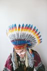 Jeune homme avec en costume traditionnel amérindien regardant vers le bas sur fond blanc — Photo de stock