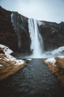 View to waterfall and river with shores covered with snow. — Stock Photo