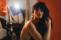 Sensuelle jeune femme frisée seins nus posant en studio . — Photo de stock