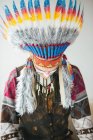Jovem em traje tradicional nativo americano olhando para baixo em pano de fundo branco — Fotografia de Stock