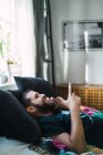 Sorrindo homem deitado no sofá em casa e falando ao telefone — Fotografia de Stock