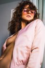 Молода жінка в піджаку на голому тілі і рожевих сонцезахисних окулярах — стокове фото