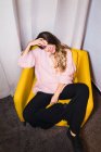 Mujer sonriente descansando en el sillón y mirando a la cámara - foto de stock