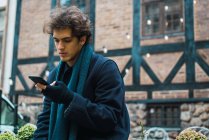 Young man browsing smartphone on street scene — Stock Photo
