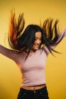 Portrait de jeune femme joyeuse sautant sur fond jaune — Photo de stock