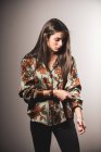 Bruna ragazza in camicia di seta manica di regolazione su sfondo grigio — Foto stock