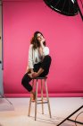 Pretty woman sitting with eyes closed on stool in studio. — Stock Photo