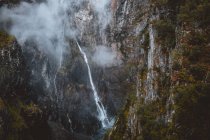 Вид с воздуха на тонкий водопад в горном лесу — стоковое фото