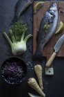 Натюрморт сирої риби на дерев'яній дошці та овочах на столі — стокове фото