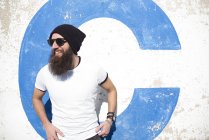 Бородатый мужчина в солнечных очках позирует на улице и смотрит в сторону — стоковое фото