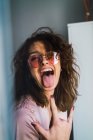 Porträt einer Frau in Jacke und Sonnenbrille, die grimmig ist und Rock-Geste zeigt — Stockfoto