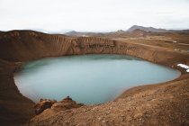 Pequeño lago con agua azul en el terreno de montaña - foto de stock
