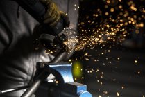 Crop mechanic hands using angle grinder on pipe at workshop — Stock Photo
