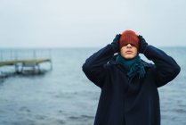 Портрет людини, що стоїть на морі і накладає капелюх на очі — стокове фото