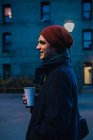 Вид сбоку человека в теплой одежде, идущего по улице с кофе — стоковое фото