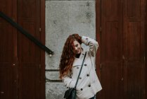 Femme rousse posant sur la rue et touchant les cheveux — Photo de stock