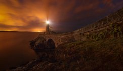 Vue panoramique sur la route et le phare à terre au crépuscule du soir — Photo de stock