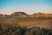 Landscape of dry field and sunlit rocks in cloudless day. — Stock Photo