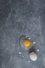 Blick von oben auf zerbrochenes rohes Ei auf grauer Oberfläche. — Stockfoto