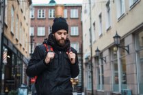 Portrait of bearded backpacker walking in city — Stock Photo