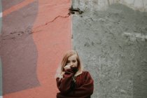 Блондинка в свитере позирует у потрепанной стены — стоковое фото