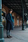 Веселий молодий чоловік у пальто стоячи на станції — стокове фото