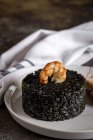 Black rice with prawns on white plate on table. — Stock Photo